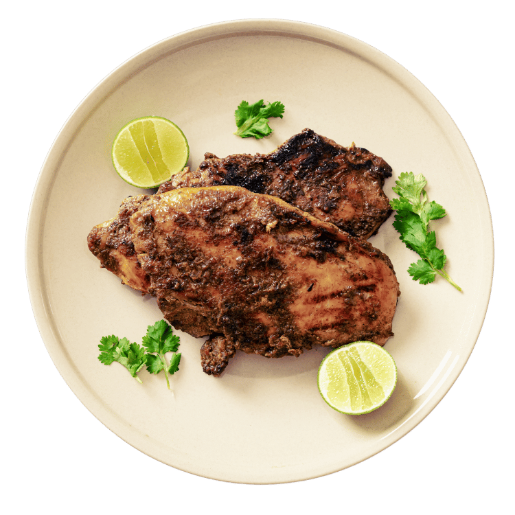 Jerked chicken on plate with lemons and parsley garnishments.